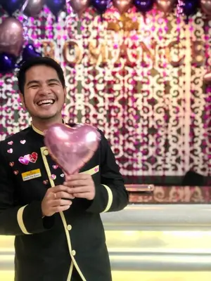 a man holding a pink heart in front of a room at Romance Hotel Sukhumvit 97 in Bangkok