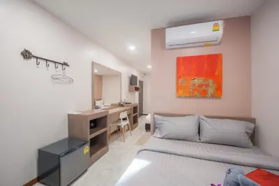 a bedroom with two beds and a desk in it at The Moon Night Hotel in Bangkok
