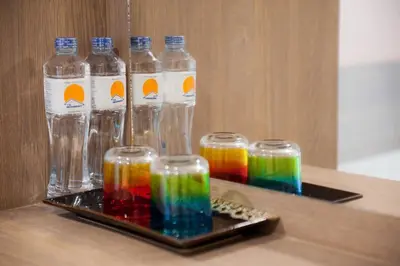 a tray with four glasses filled with rainbow liquid at The Moon Night Hotel in Bangkok