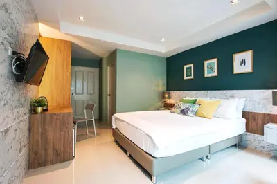 a bedroom with a large bed and green walls at NW Apartment Lasalle 59 in Bangna