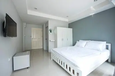 a bedroom with a white bed and a flat screen tv at NW Apartment Lasalle 59 in Bangna