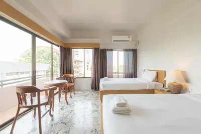 a hotel room with two beds and a table and chairs at Nonthaburi Palace Hotel in Nonthaburi