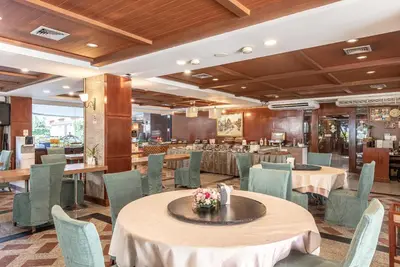 a dining room with tables and chairs and a restaurant at Nonthaburi Palace Hotel in Nonthaburi