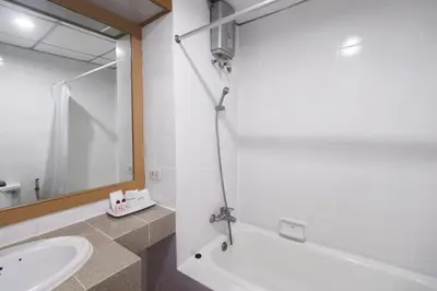 a bathroom with a sink and a tub and a mirror at Nonthaburi Palace Hotel in Nonthaburi