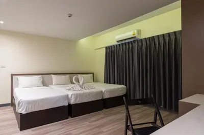 a hotel room with two beds and a chair at Siam Star Hotel in Bangkok
