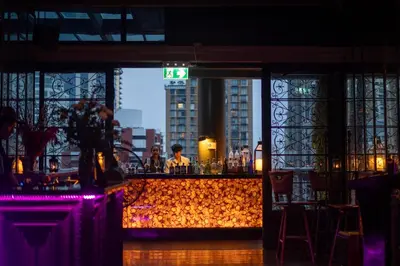 a bar in a restaurant with a view of a city at Hotel Muse Bangkok, Autograph Collection by Marriott in Bangkok