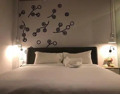 a bedroom with a bed with white sheets and lights at Bedspread Hostel in Bangkok