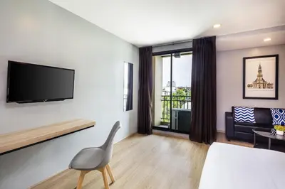 a living room with a bed and a television on a wall at Narra Hotel in Bangkok