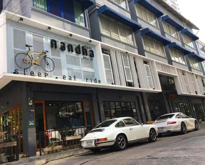 a white car parked in front of a building at Nandha Hotel in Bangkok