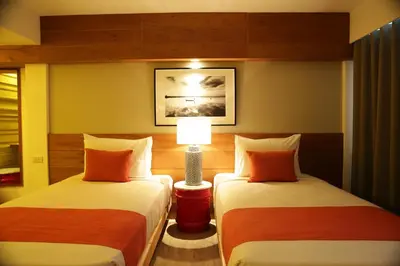 a hotel room with two beds and a lamp at Nandha Hotel in Bangkok