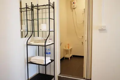a bathroom with a mirror and a shelf with towels at 12/14 HOME Studio in Bangkok