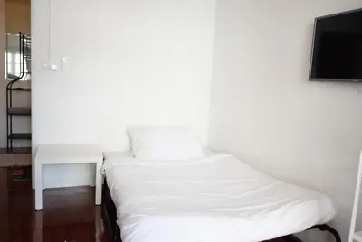 a white bed in a room with a tv at 12/14 HOME Studio in Bangkok