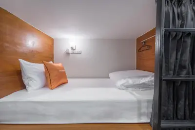 a bedroom with a white bed with a wooden headboard at Tiny Taladnoi Hostel in Bangkok