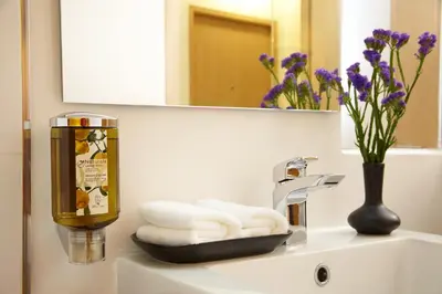 a bathroom sink with a bottle of soap and towels at Citypoint Hotel in Bangkok