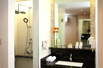 a bathroom with a sink and a large mirror at Citypoint Hotel in Bangkok