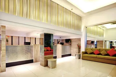 a lobby with a green couch and red chairs at Citypoint Hotel in Bangkok