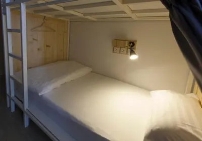 two bunk beds in a small room with a light at Pinto Hostel in Bangkok