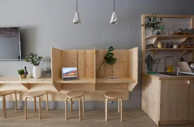 a kitchen with a wooden counter with stools and a table at Pinto Hostel in Bangkok