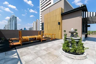 a rooftop patio with a bench and trees on a building at THEA Private Suites by TH District in Bangkok