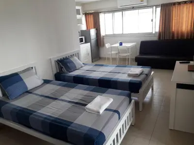 a bedroom with two beds and a living room at New Room in Nonthaburi
