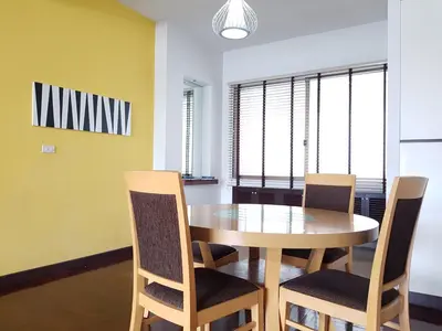 a dining room with a wooden table and chairs at P.T. Court in Bangkok