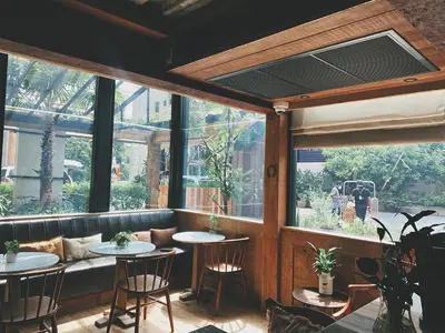 a restaurant with two tables in a room with windows at Abloom Exclusive Serviced Apartments in Bangkok