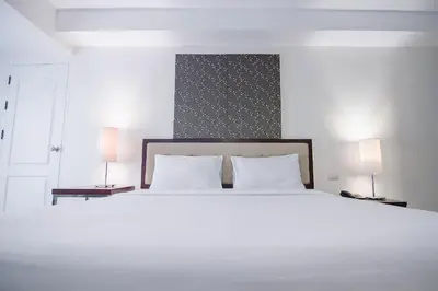 a bedroom with a large white bed with two lamps at Romance Hotel Bangna in Bangkok
