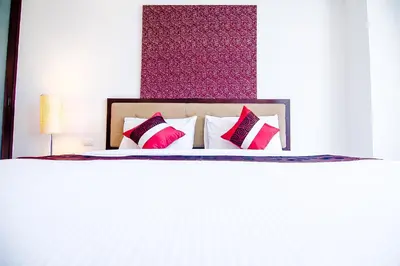 a bed with pink and white pillows on it at Romance Hotel Bangna in Bangkok