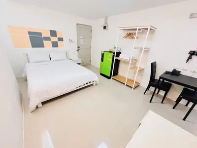 a white bedroom with a bed and a desk at PDA Lord Hotel in Bangkok