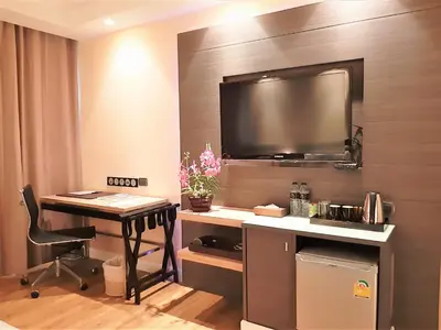 a room with a desk and a tv on a wall at Amora NeoLuxe Suites Hotel in Bangkok