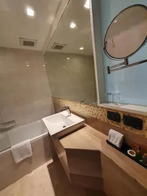a bathroom with a sink and a mirror and a tub at Amora NeoLuxe Suites Hotel in Bangkok