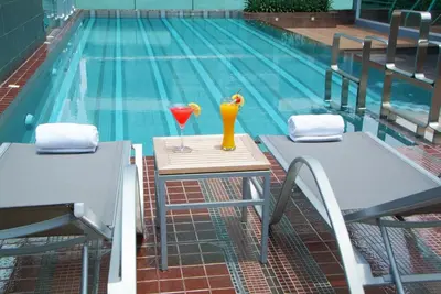 two glasses on a table next to a swimming pool at Amora NeoLuxe Suites Hotel in Bangkok