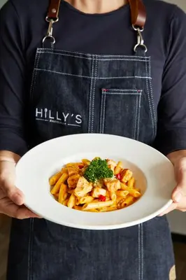 a person holding a plate of pasta and vegetables at The Quarter Ladprao by UHG in Bangkok
