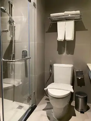 a bathroom with a toilet and a shower and towels at The Quarter Ladprao by UHG in Bangkok