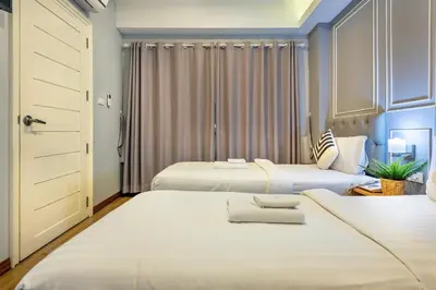 a bedroom with two beds and a closet at De Lavender Bangkok Hotel in Bangkok