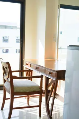 a wooden desk with a chair next to a window at White House Bizotel in Bangkok
