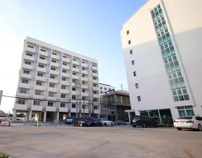 a large white building with cars parked in a parking lot at White House Bizotel in Bangkok