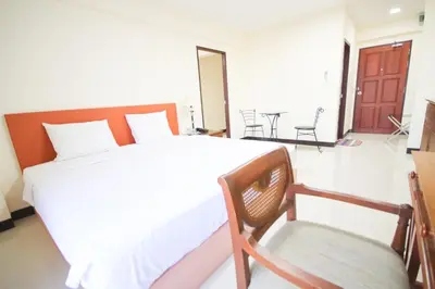 a bedroom with a large bed and a chair at White House Bizotel in Bangkok