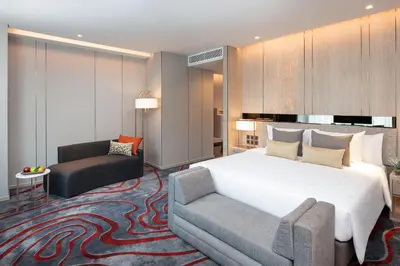 a bedroom with a bed and a chair and a couch at Hotel Nikko Bangkok in Bangkok