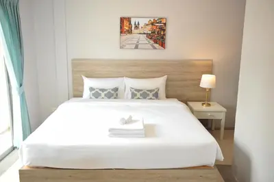 a bedroom with a large white bed and a lamp at Drop Inn Bangkok in Bangkok