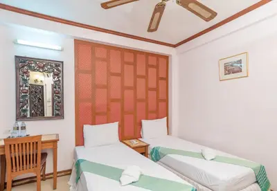 a room with two beds and a table and a mirror at New Siam III Guest House in Bangkok