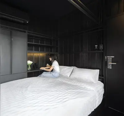 a woman sitting on a bed with a laptop at Kloem Hostel in Bangkok