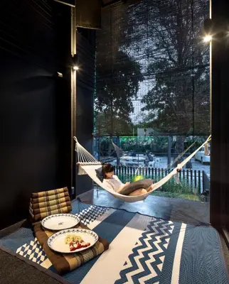 a person sitting in a hammock in a room at Kloem Hostel in Bangkok