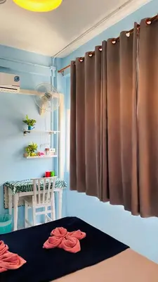 a room with a bed and a table and a window at 4J Lodge in Bangkok