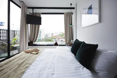 a bedroom with a white bed with a large window at Ob-Oon Boutique Bed & Breakfast in Bangkok