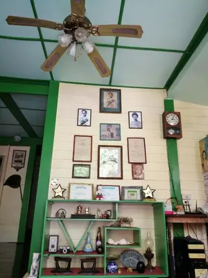 a ceiling fan and shelves with pictures on a wall at Baan Tepa Boutique House in Bangkok