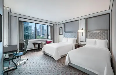 a hotel room with two beds and a large window at The Athenee Hotel, a Luxury Collection Hotel, Bangkok in Bangkok
