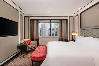 a hotel room with a bed and a chair and a window at The Athenee Hotel, a Luxury Collection Hotel, Bangkok in Bangkok