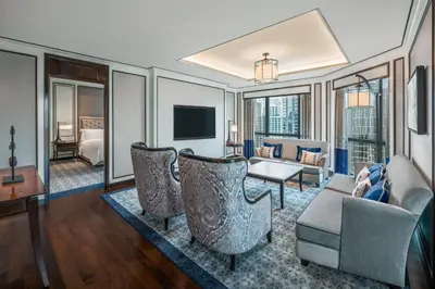 a living room with a couch and chairs and a television at The Athenee Hotel, a Luxury Collection Hotel, Bangkok in Bangkok