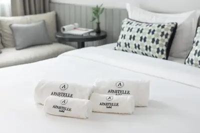 two beds in a hotel room with towels on them at Apartelle Jatujak Hotel in Bangkok
